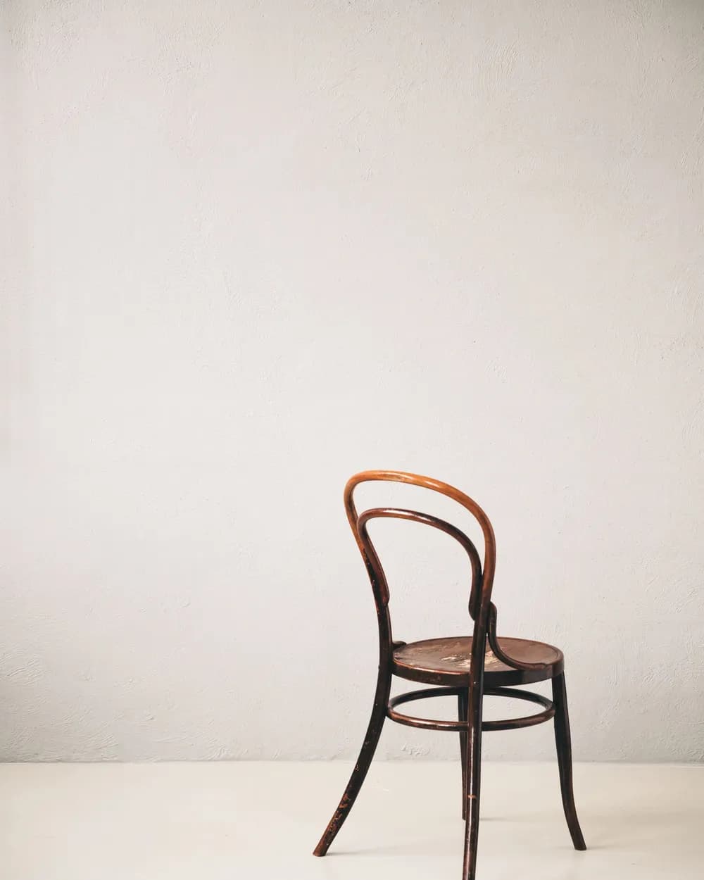 A wooden chair against a plain studio wall.