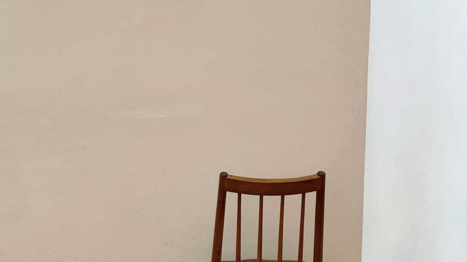A wooden chair against a bare white wall.