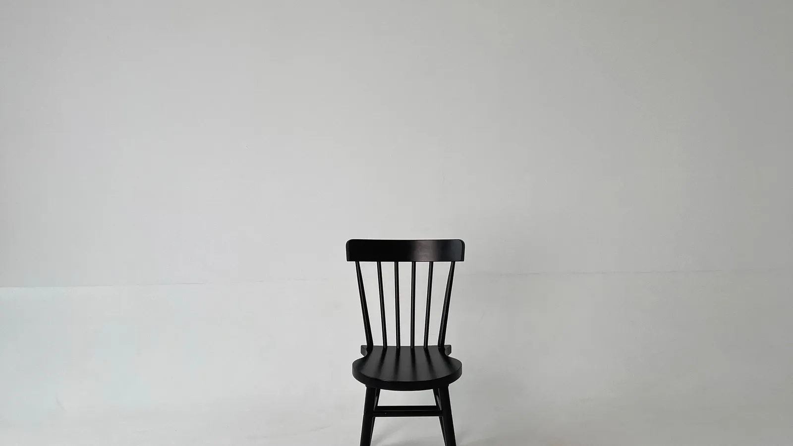 A black chair in a plain studio setting.
