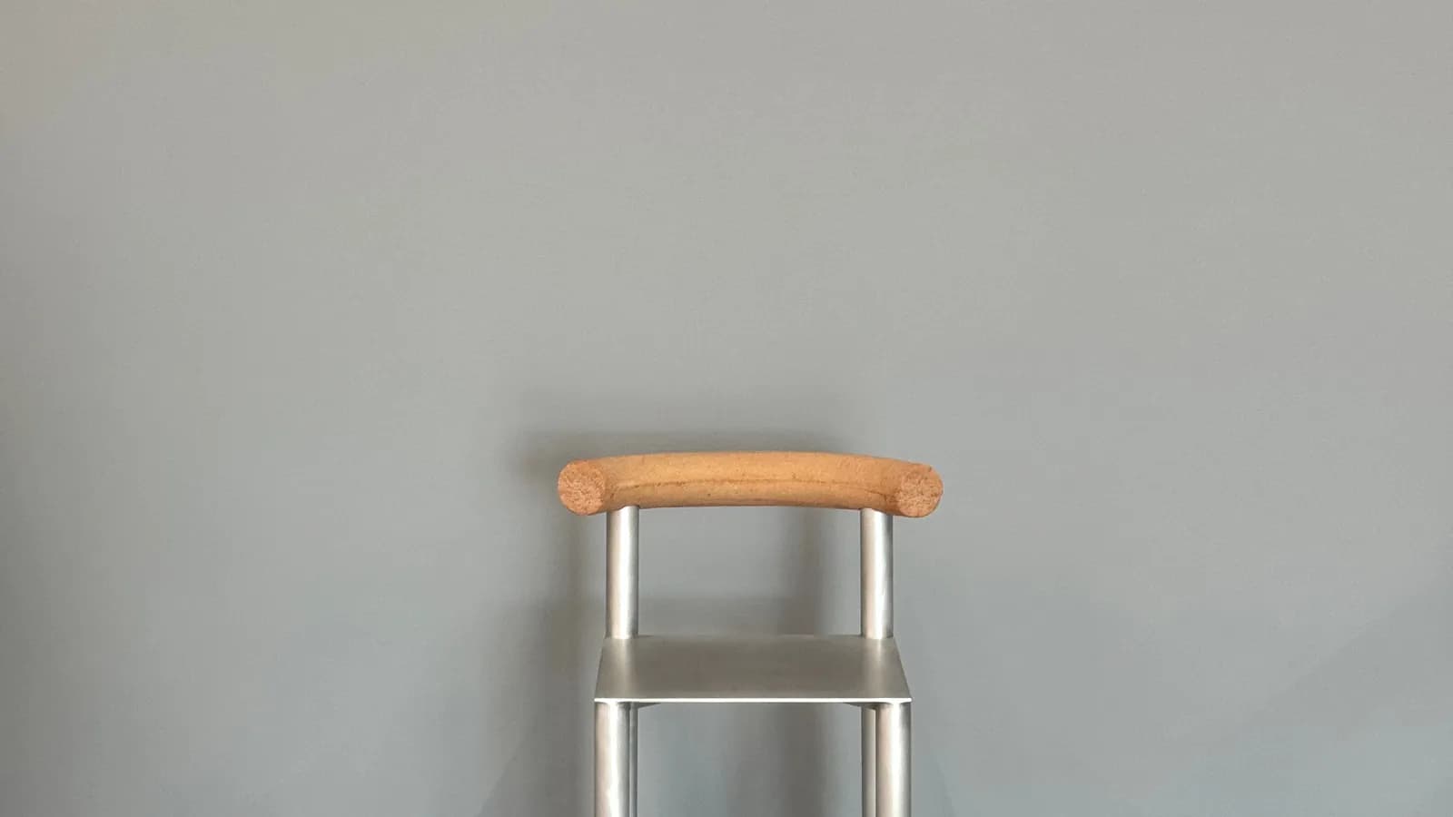 A metal chair with wooden accents against a grey wall.