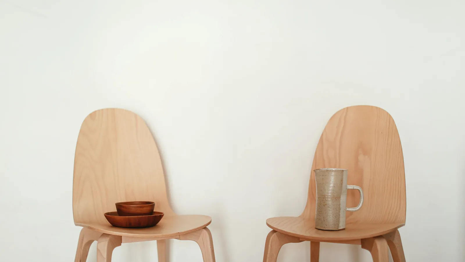 Two wooden chairs with a ceramic mug and bowls.