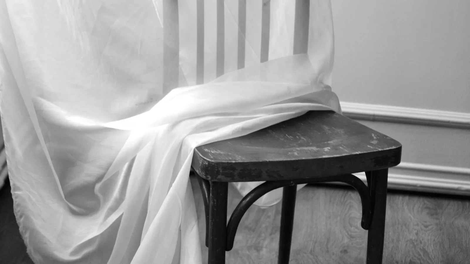 A wooden chair draped with white fabric.