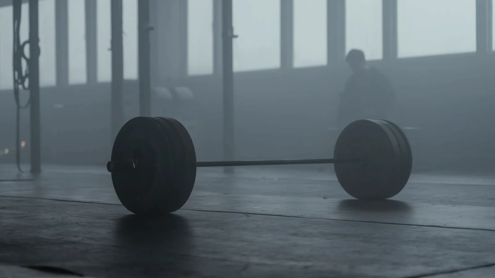 A loaded barbell on a gym floor with haze behind it.