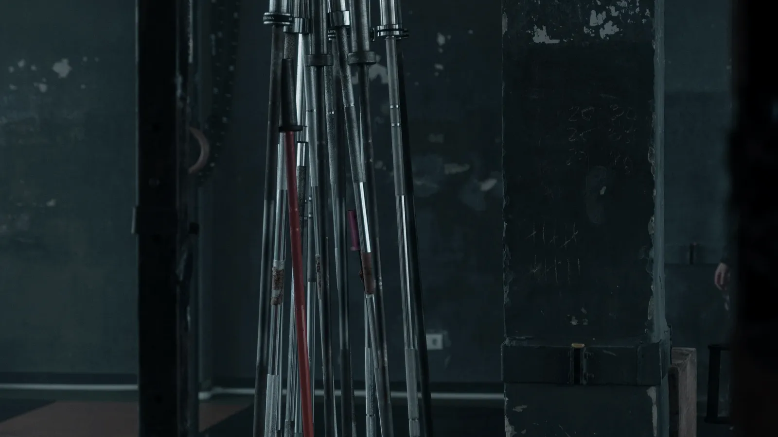 Stacked barbells against an industrial wall.