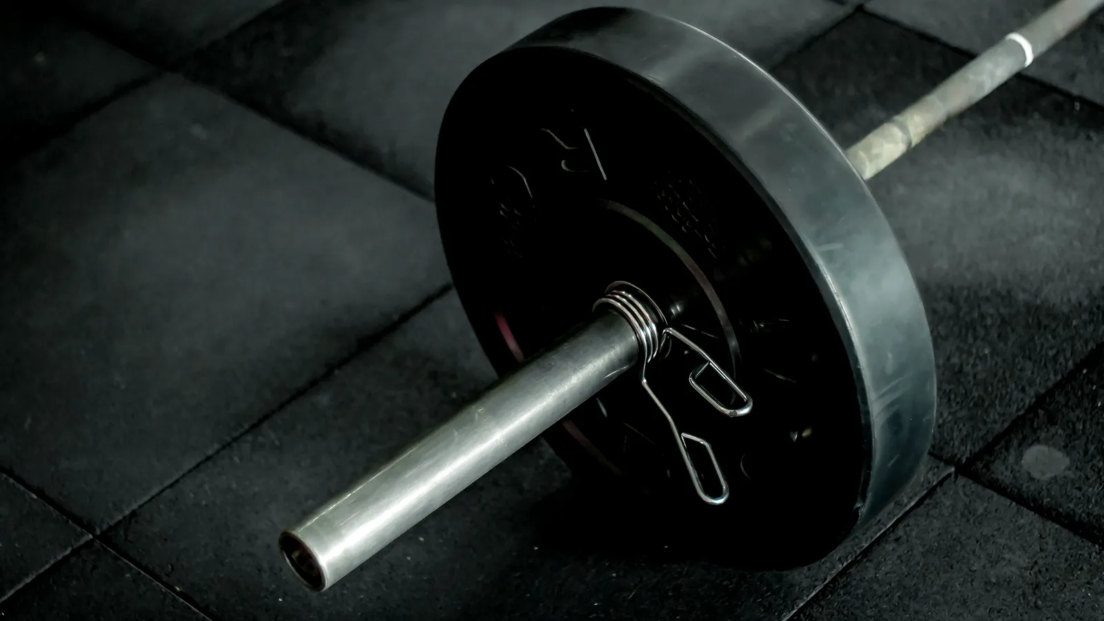 A barbell loaded with heavy plates on a dark floor.
