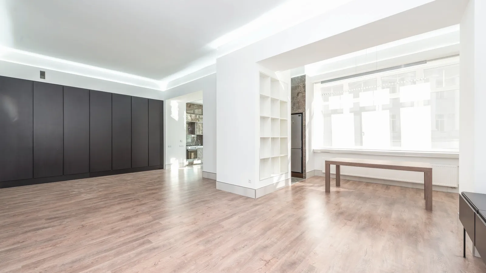 An empty room with hardwood flooring and low sunlight falling across it.