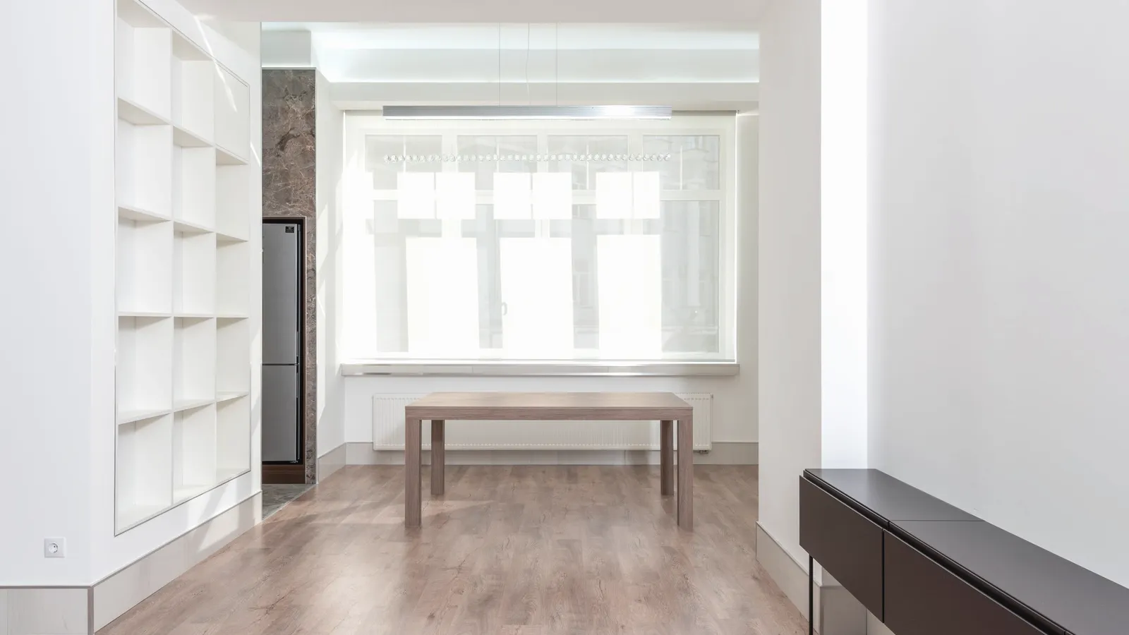 A living room with wooden flooring and simple furniture.