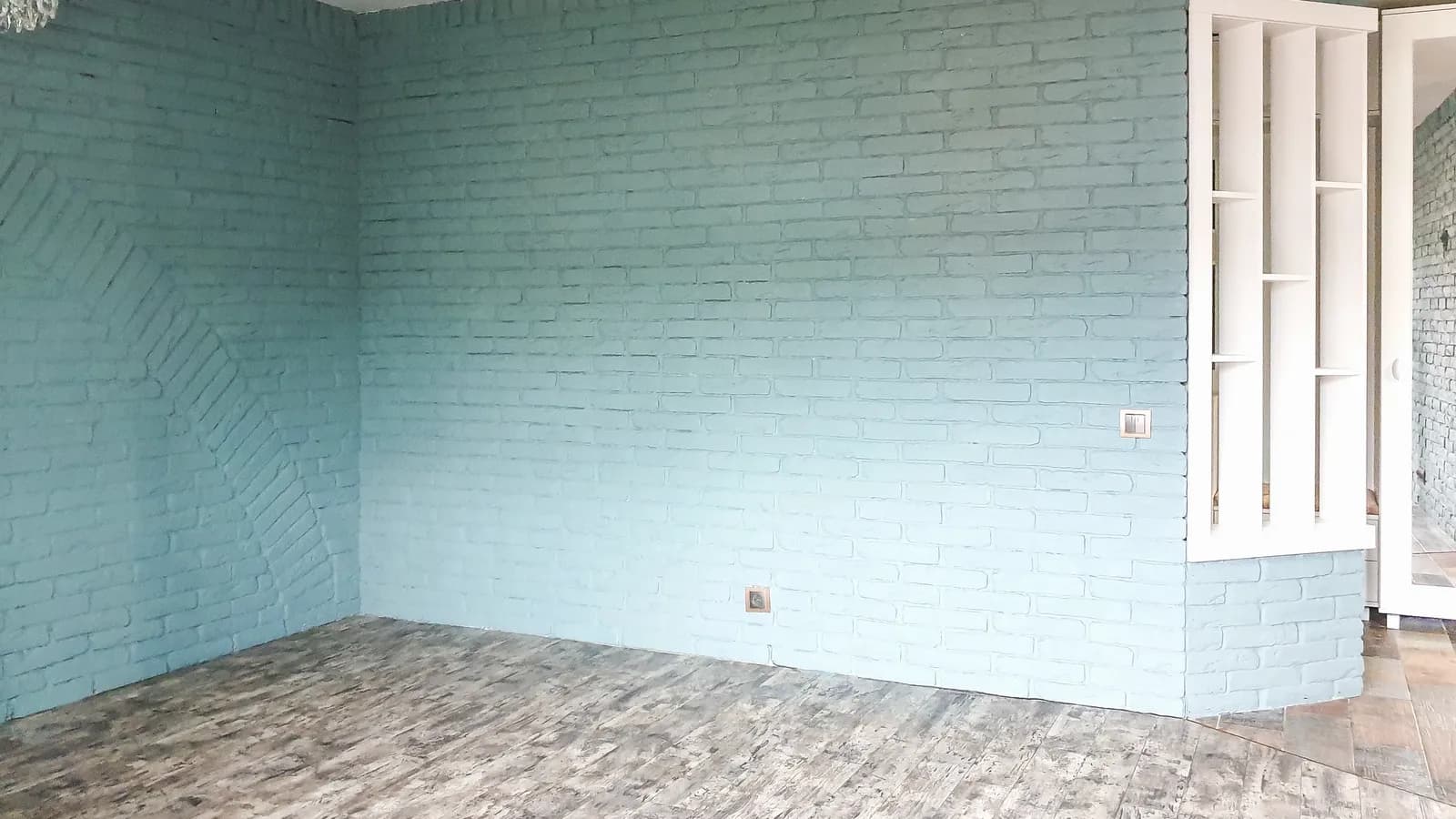 A spacious room with an exposed brick wall and rustic boards.