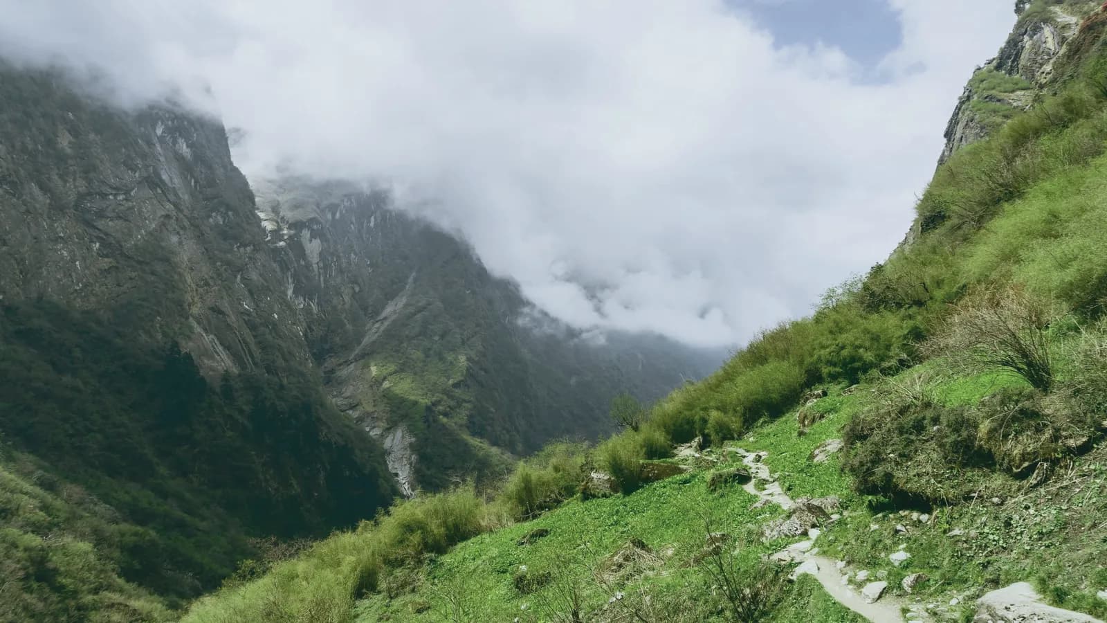 A path on a green ridge with cloud rolling over the spur.