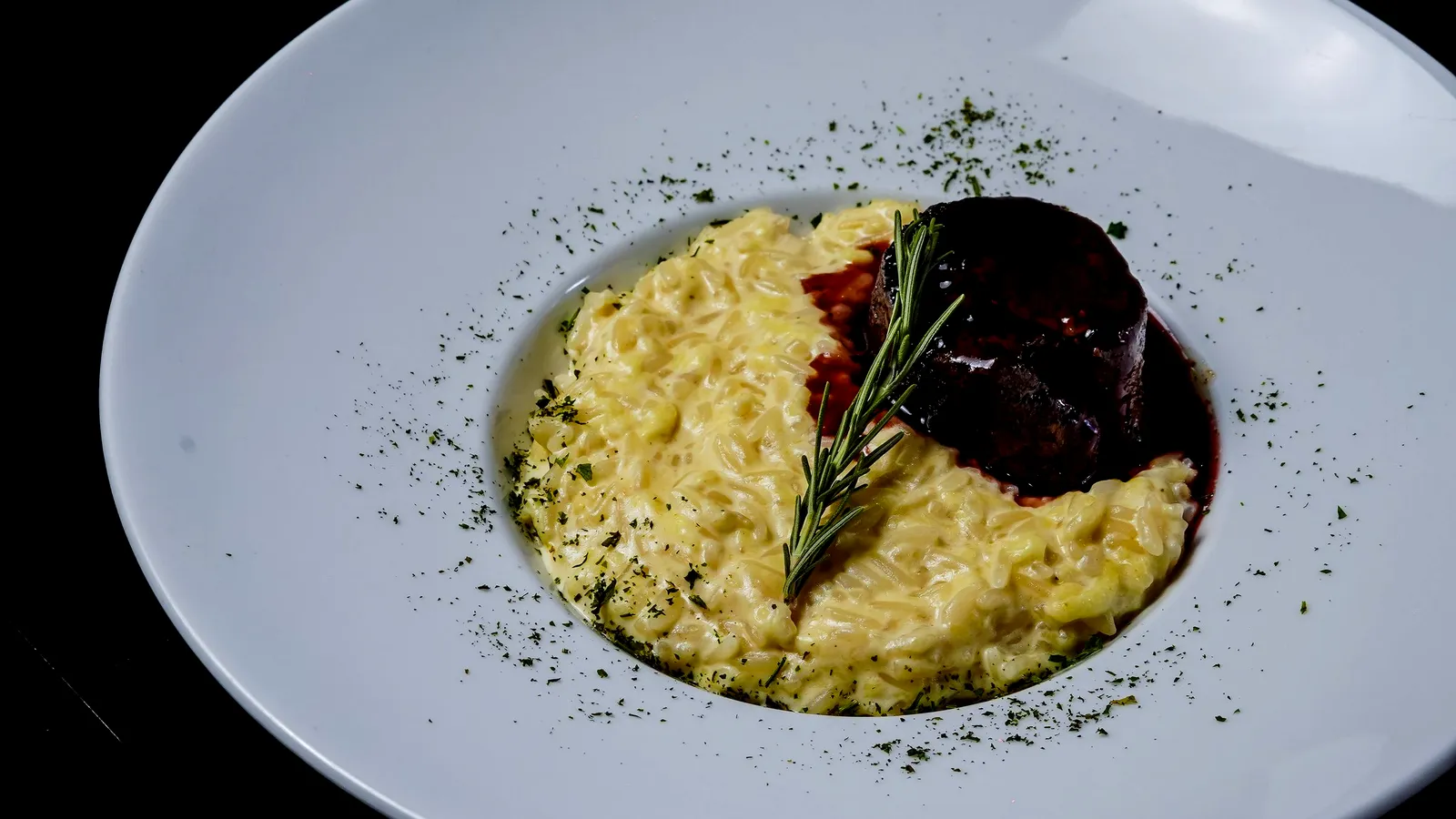 Risotto with rosemary, plated on dark stone.