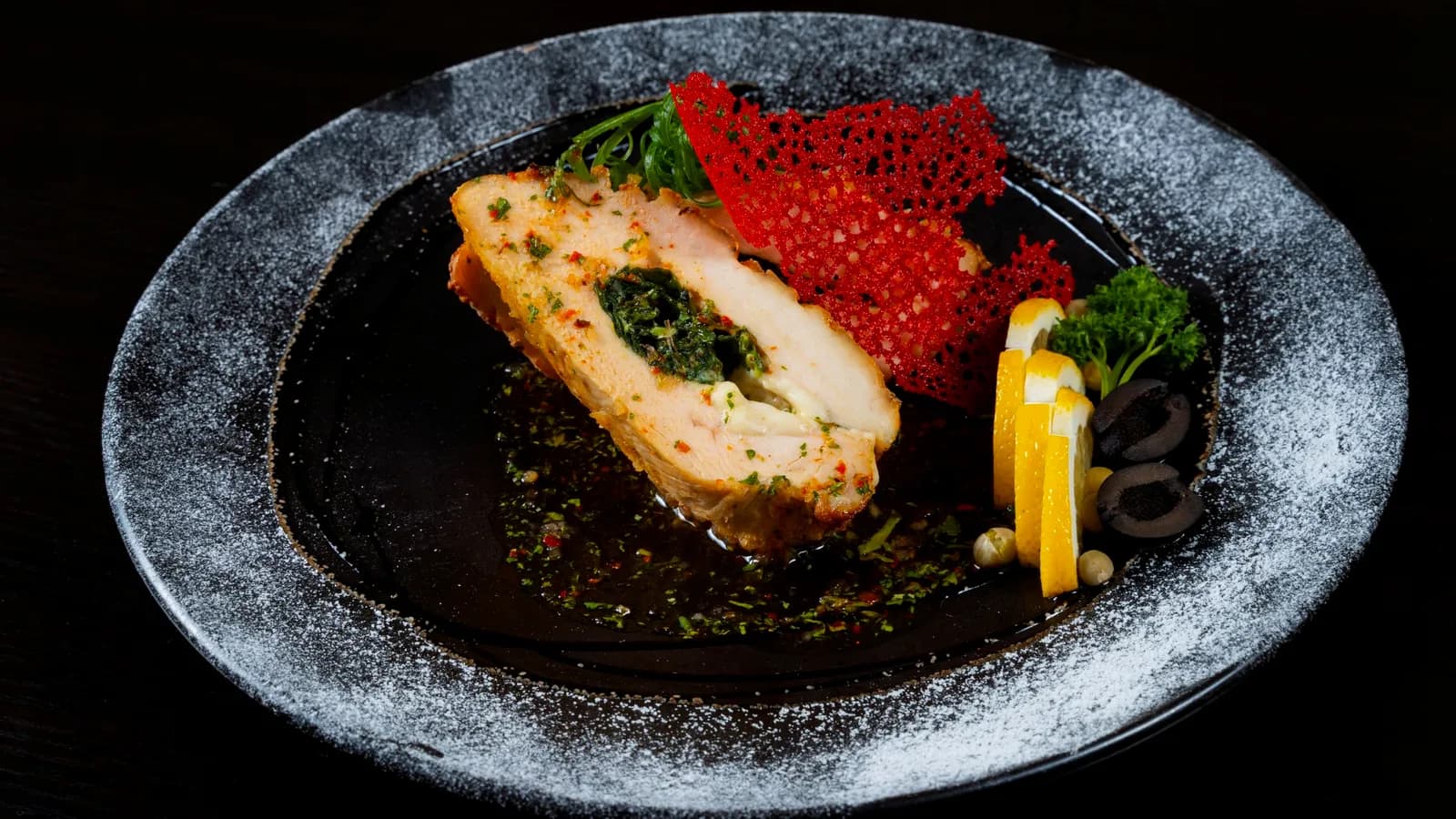 A salmon course with bright garnishes on dark stone.