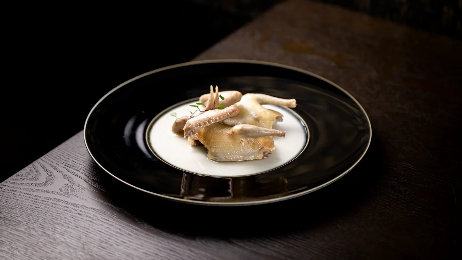 A whole roast bird on a dark serving plate.