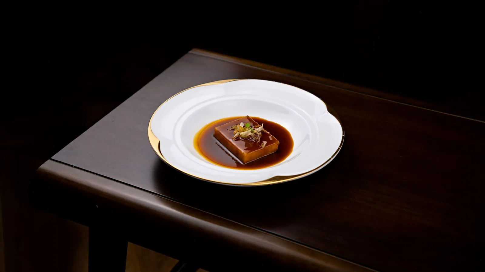 A dessert on fine porcelain with a dark sauce.