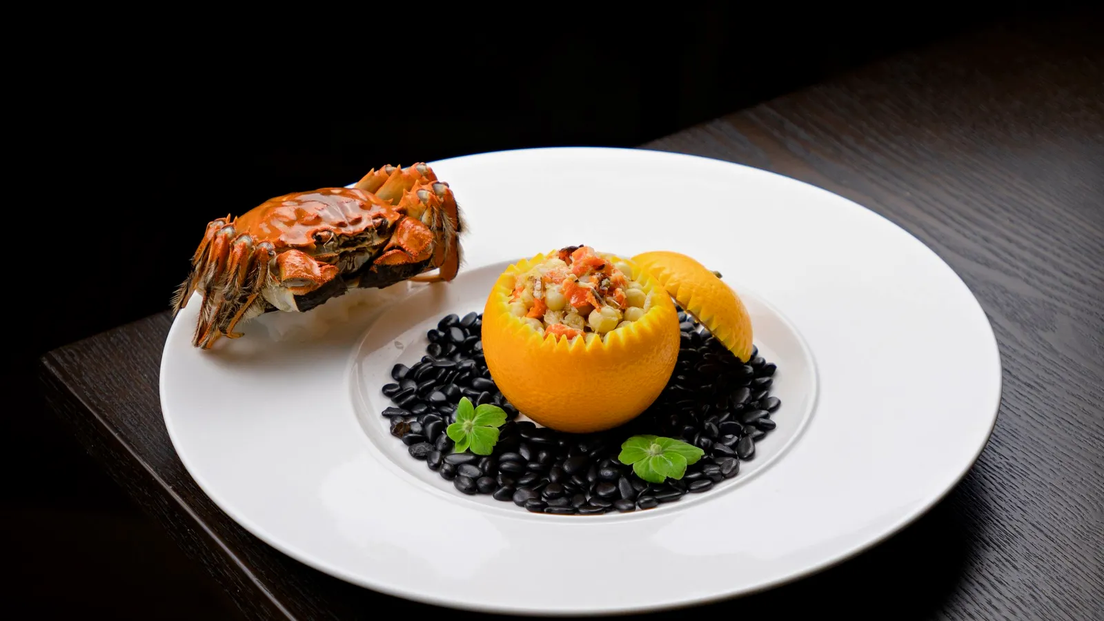A lobster course plated on dark stone under a single warm light.