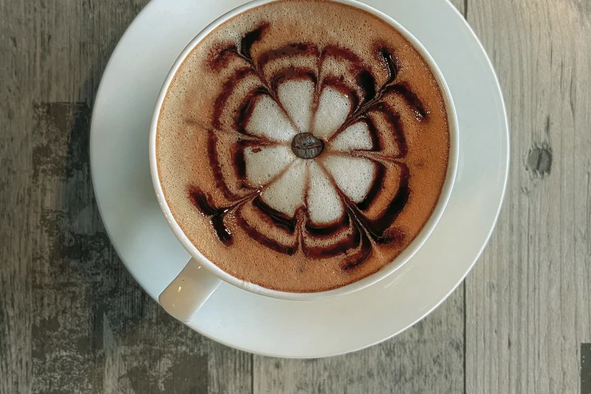 A cup of coffee seen from above, latte art in a white ceramic cup.