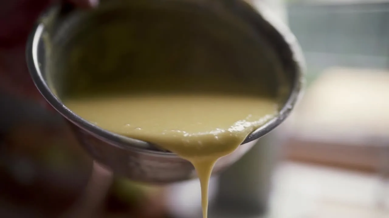 Batter poured slowly into a bowl in close-up.